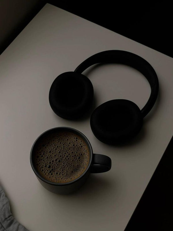 Black coffee and headphones on a dark desk